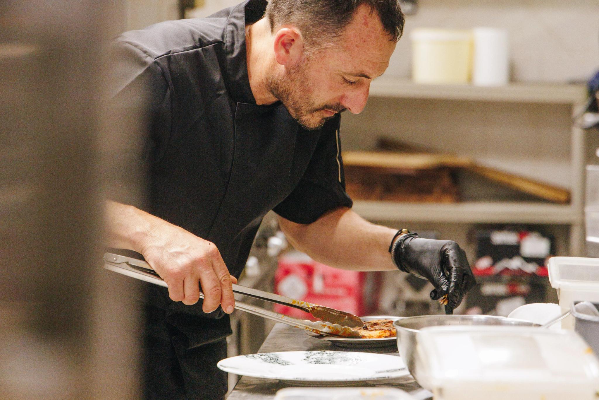 Chef en cuisine restaurant corse préparant un plat traditionnel avec précision