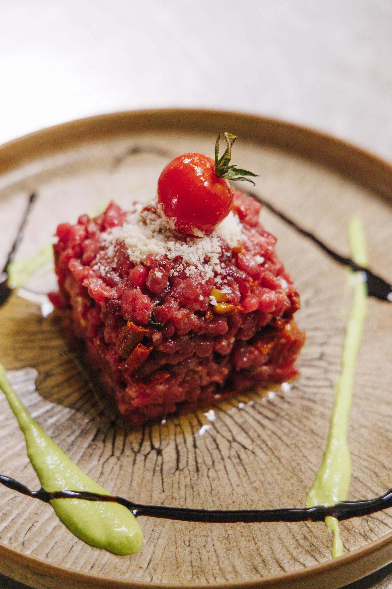 Tartare de viande rouge présenté au restaurant corse avec tomate cerises et décoration de sauce