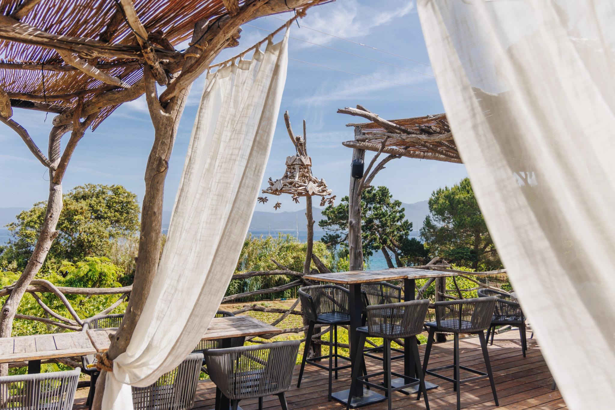 Restaurant en Corse avec terrasse panoramique, mobilier moderne et voiles blanches sous les arbres