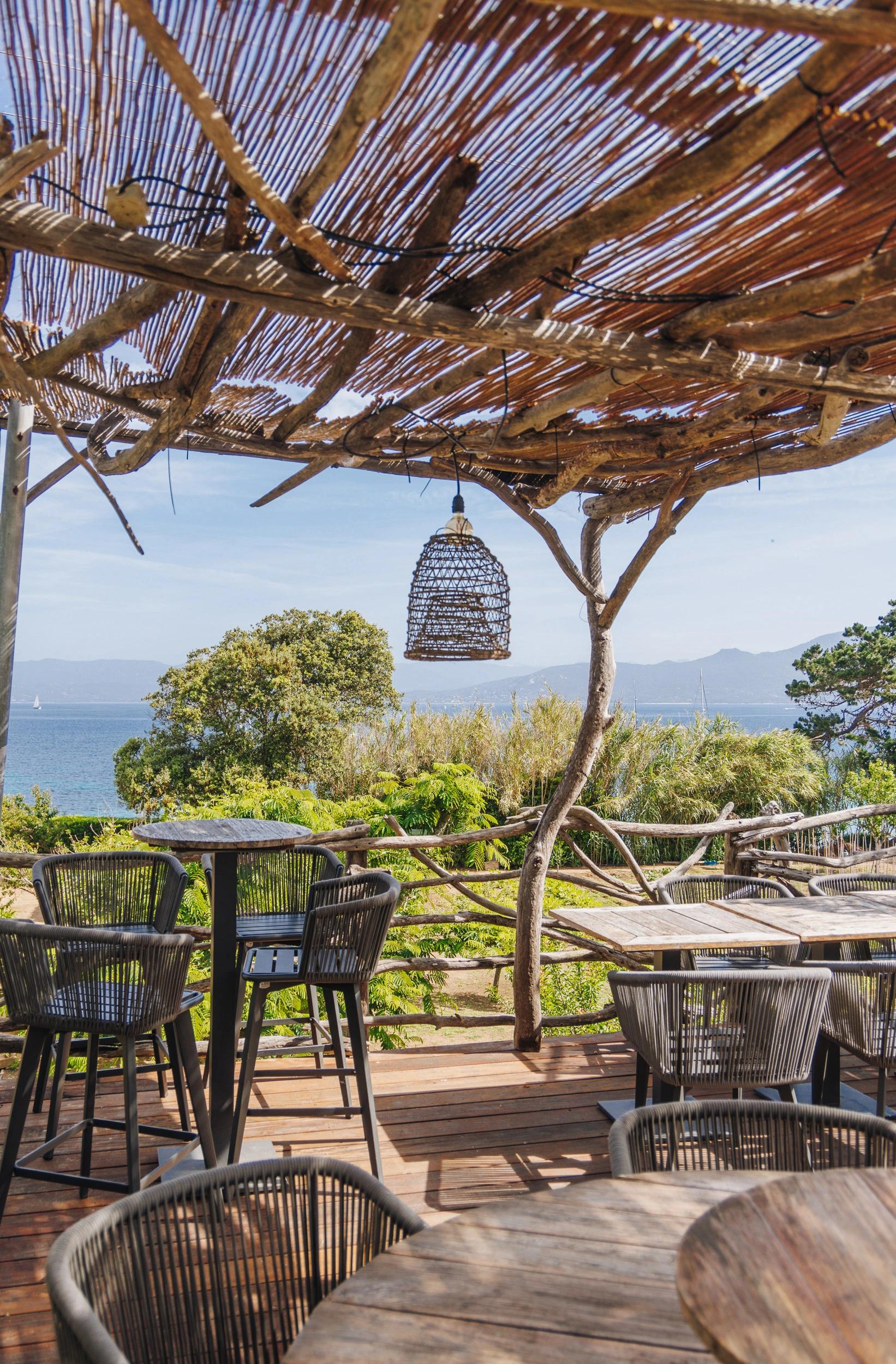 Restaurant en Corse avec terrasse vue mer, mobilier en rotin et pergola en bois naturel