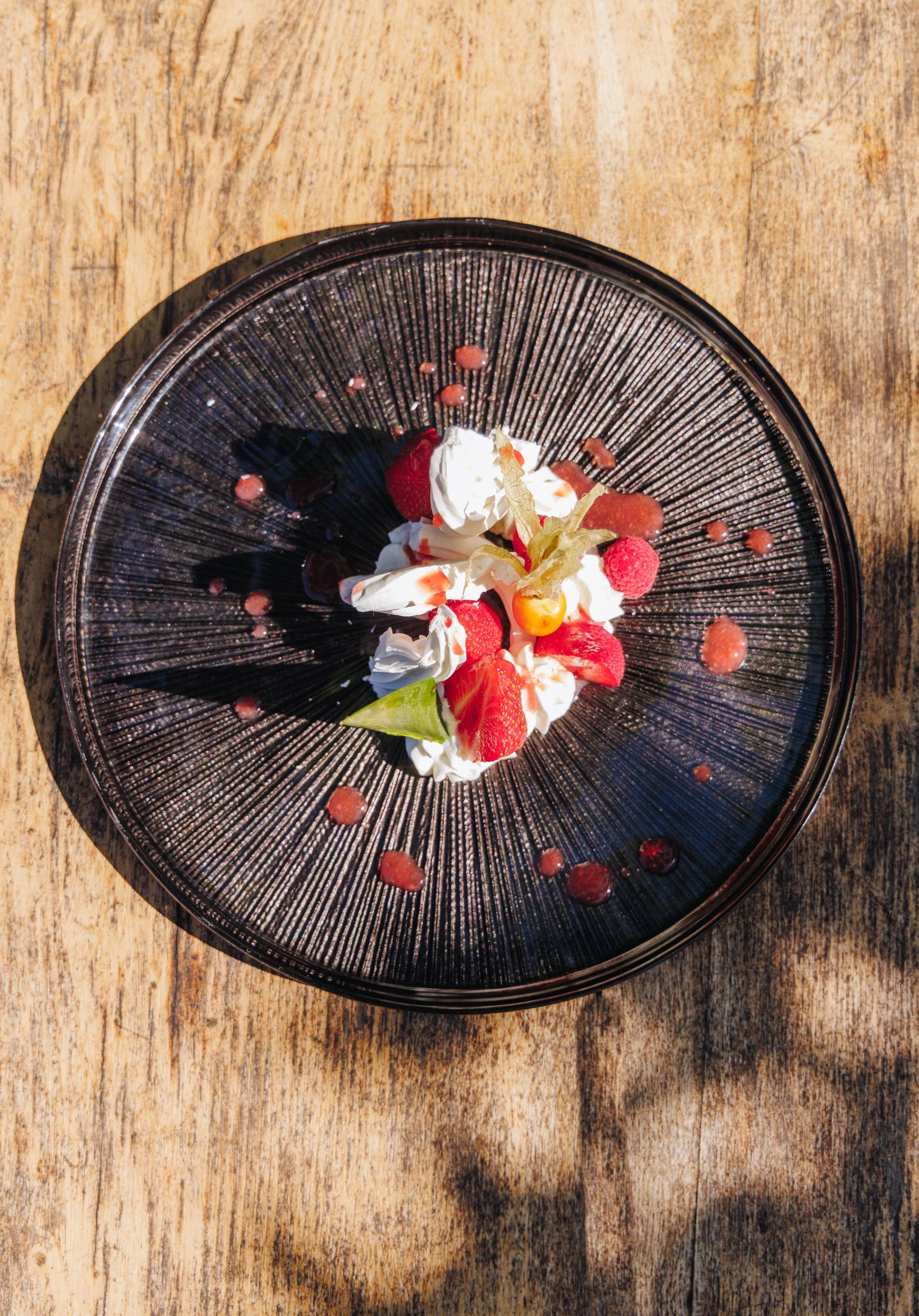 Assiette gastronomique de restaurant corse avec fleurs et fruits rouges sur fond noir